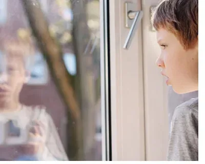 Enfant autiste regardant par la fenêtre : prévenir le risque de fugue avec un GPS